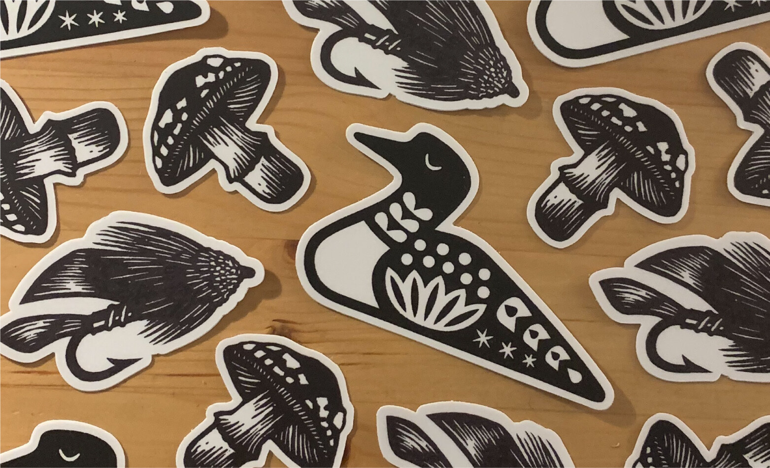 Sticker sheet with loon, mushrooms, and fishing fly illustrations